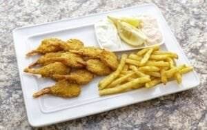 Dearborn's Fried shrimp and french fries on a white plate celebrate the delectable flavors of seafood.
