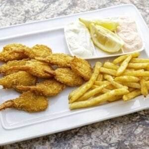 Seafood platter of fried shrimp and french fries on a white plate.