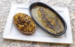 A plate with a Mediterranean-inspired dish featuring a fish and rice.