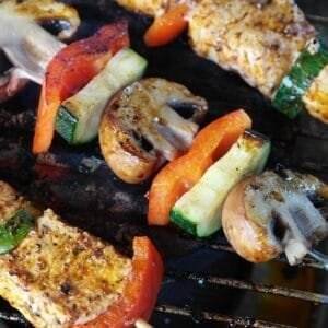 Grilled meat skewers with chicken and vibrant vegetables like mushrooms, red bell peppers, and zucchini, sizzling perfectly on the grill.