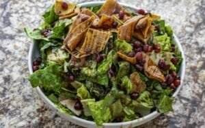 A Mediterranean bowl of salad with pomegranate and walnuts.