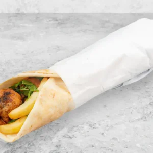A chicken shawarma wrap with fries and greens, partially wrapped in white paper, placed on a gray stone surface—a delicious alternative to a Fried Shrimp Sandwich.